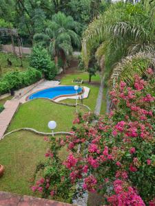 耶尔瓦布埃纳Casa Al pie del Cerro的一个带游泳池和粉红色鲜花的花园