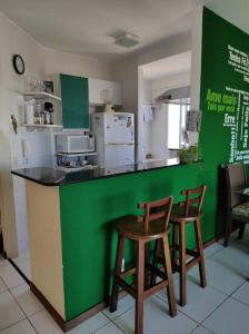 瓜拉派瑞Seu Apê na Enseada Azul - Bacutia !!!的厨房设有绿色柜台上的两张木凳