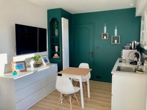 蒙贝利亚尔Appartement avec terrasse et parking gratuit accolé的厨房设有绿色的墙壁和桌椅