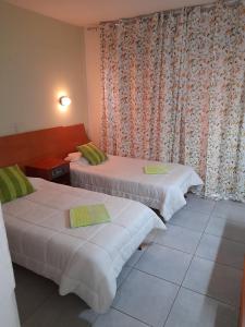 拉纳卡奥妮思罗斯酒店的配有窗帘的酒店客房内的两张床