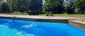 PréverangesChambres d’hôtes La Joyeuse的一个带木甲板和蓝色海水的游泳池