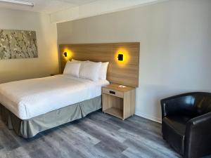 魁北克市Econo Lodge Airport Quebec的配有一张床和一把椅子的酒店客房