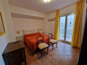 陶尔米纳德格利阿格鲁米住宿酒店的一间卧室配有带橙色床单和两把椅子的床