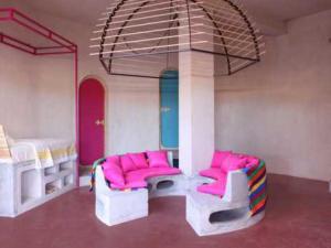 Nefta达尔日酒店的带两张双层床和粉红色椅子的客房