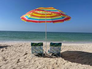 阿吉曼Beachfront paradise just minutes from Dubai的海滩上一把遮阳伞下的两把椅子
