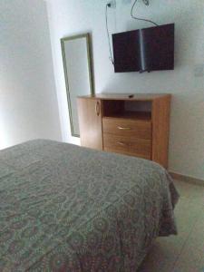 玛德琳港Hermoso depto en excelente ubicacion的一间卧室配有一张床和一个带平面电视的梳妆台。