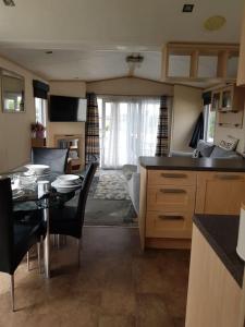 本布里奇Home from Home cosy caravan的厨房以及带桌椅的起居室。