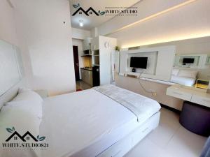 TambakosoWhite Studio Group Surabaya - WS 821 at Amega Crown Residence的卧室配有白色的床和电视。