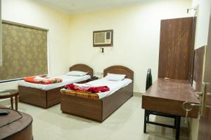 加尔各答Hotel Komala Vilas的客房设有两张床、一张桌子和一张书桌。