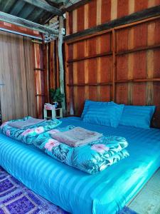 Ban KlangHomestay&ChaoleySeafoodrestaurant的一张蓝色的大床,位于带木墙的房间