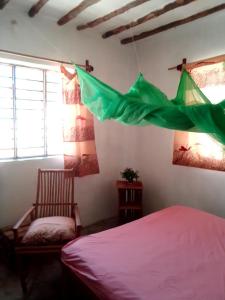 平圭Bibi Mrembo Guesthouse的一间卧室配有床和椅子,并悬挂着绿色旗帜