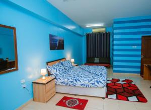 达累斯萨拉姆Queens Rentals - Studio Apartments - Village Walkway - Masaki - Dar es Salaam的一间拥有蓝色墙壁的卧室,配有一张床和一张桌子