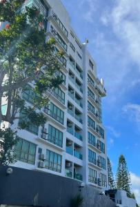 大雅台One Tagaytay Place Hotel Suites OFFICIAL ACCOUNT的一座高大的白色建筑,前面有一棵树