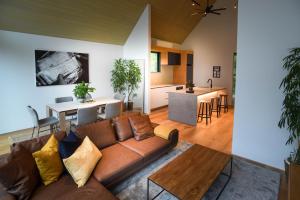 白马村Prominence by The Hakuba Collection的一间带棕色沙发的客厅和一间厨房