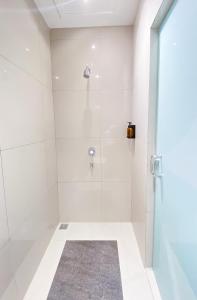 班达亚齐Alhambra Hotel Banda Aceh的白色的浴室设有玻璃门淋浴