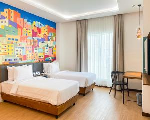 班达亚齐Alhambra Hotel Banda Aceh的两张位于酒店客房的床,墙上挂着一幅画