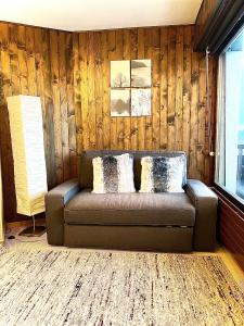 莱斯克伦斯Cosy Studio for 5 near ski lift, Les Gentianes的木墙的房间里一张沙发