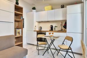 莱萨布勒-多洛讷Tiny studio terrasse, hypercentre la plage à 2 pas !的厨房配有白色橱柜和桌椅