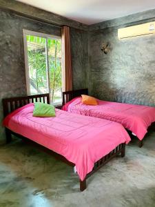北冲北冲版衫理南度假村的配有粉红色床单和窗户的客房内的两张床