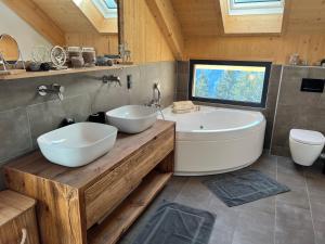 Bergchalet Stolzalpe的浴室配有2个白色水槽和1个浴缸。
