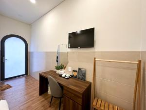 永隆VÂN TRANG GARDEN HOTEL 2的一间房间,配有一张桌子和一台墙上的电视