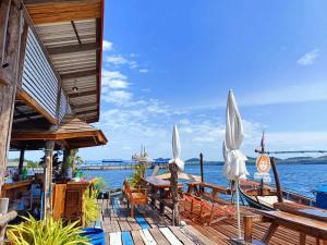 Ban KlangHomestay&ChaoleySeafoodrestaurant的水面上带桌子和遮阳伞的木甲板