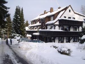 巴特萨克萨恩格努尔格宾馆的一座有雪盖的建筑,前面有汽车停放
