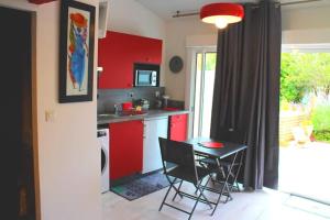 拉康提内勒La Cotinière, studio avec cuisine 50 m de la plage的厨房配有红色橱柜和桌椅