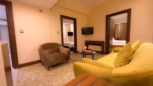 巴格达Shaheen Hotel Baghdad的客厅配有沙发、椅子和电视
