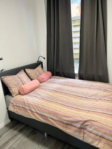 莱顿‘T Singeltje的一间卧室配有带粉红色枕头的床和窗户。
