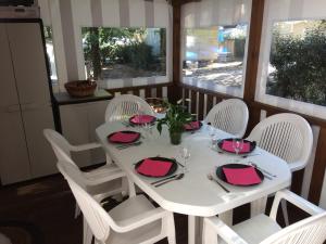 圣布里文莱丝皮恩Mobilhome 3 chambres tout confort, proche de la plage的一张带白色椅子的桌子和一张带粉红色餐巾的白色桌子