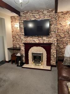 绍尔Park cottage High Crompton的客厅设有石制壁炉和平面电视。