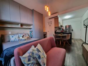 巴鲁埃里Flat luxo, mobiliado c/ ar, wi-fi, pisc. e academia的一间带粉色沙发的客厅和一间厨房