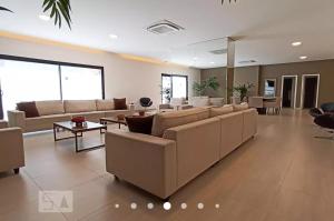 巴鲁埃里Flat luxo, mobiliado c/ ar, wi-fi, pisc. e academia的带沙发和桌子的大型客厅