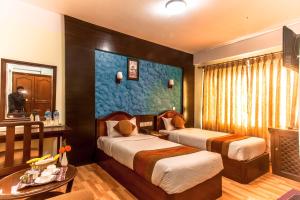 加德满都Samsara Boutique Hotel的酒店客房设有两张床和一张桌子。