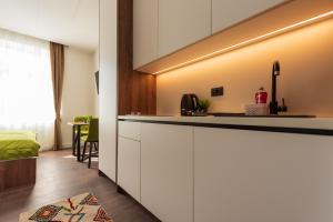 萨拉热窝Apartments EMERALD Free Garage Parking的一间厨房,配有白色的橱柜和一张位于客房内的床