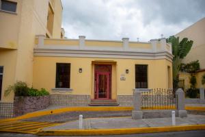特古西加尔巴麦克阿瑟酒店的街上有黄色的建筑,有红色的门