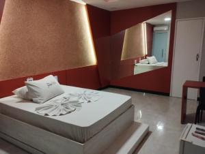 阿拉卡茹Motel FLEX LOVE LAMARAO的卧室配有一张带镜子的白色大床