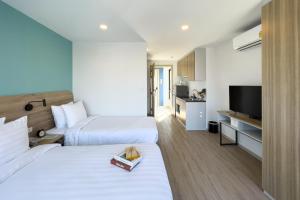 曼那Wellness Stay & Hotel Sukhumvit 107的酒店客房设有两张床和电视。