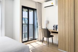 曼那Wellness Stay & Hotel Sukhumvit 107的一间卧室配有一张床、一张书桌和一个窗户。