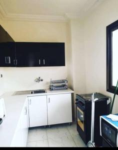 瓦加杜古Appartement luxueux ouaga2000(2 chambres )的厨房配有白色橱柜和黑炉。