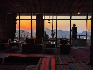 瓦迪穆萨洛矶山酒店 的站在一个房间,眺望着日落的男人