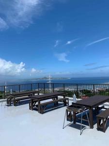 本部Yukurina Resort Okinawa的一个带野餐桌的庭院,背景是大海