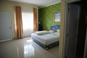 茂物Griya Kayana Inn and Villas的一间设有床铺的卧室,位于一个绿色壁纸的房间