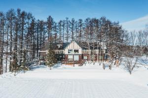 美瑛町緩慢‧北海道民宿的树前雪中的房子