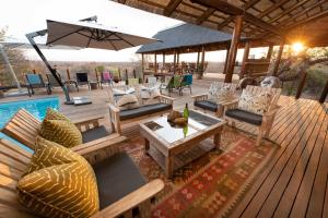 巴卢莱自然保护区腊肠树野生动物园露营地旅馆的一个带桌椅和遮阳伞的甲板