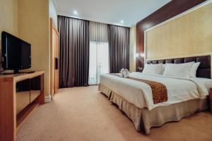 泗水Surabaya Suites Hotel Powered by Archipelago的一间酒店客房,配有一张大床和一台平面电视