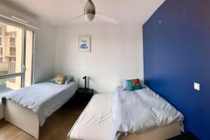 卡布勒通APPARTEMENT PLAGE EN RESIDENCE ENTIER 2 CHAMBRES的蓝色墙壁客房的两张床