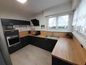 Coudekerque-Branchezouzoubelle的厨房配有黑色橱柜和木制台面