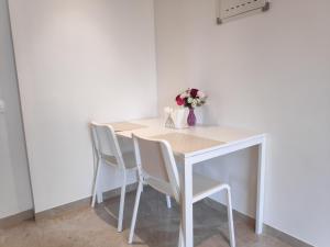 孟买Maxxvalue Apartment Hiranandani Powai的一张带椅子的白色桌子和花瓶
